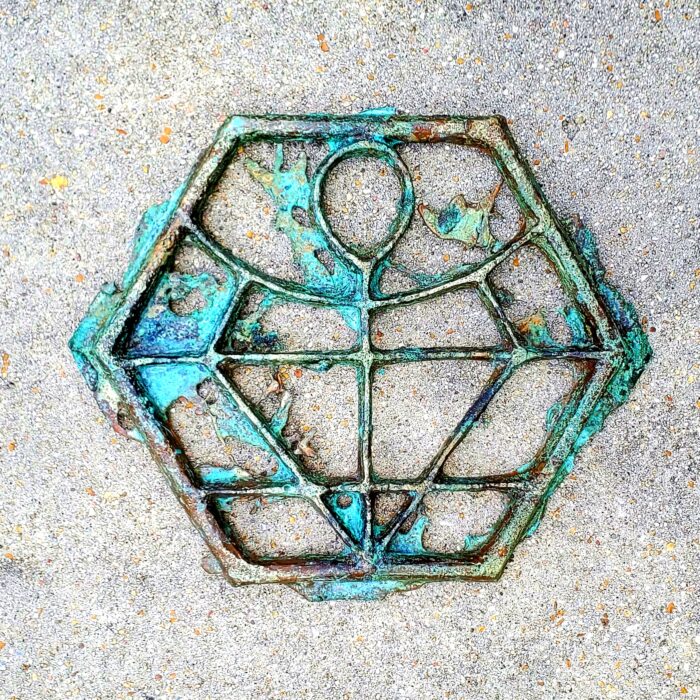 Fine art wall hanging metal sculpture for sale. Sand cast bronze filigree with an antiqued blue green patina. Abstract concept art with a unique story. The symbol of life and amulet of protection inside a geometric hex shape. The Sigil of the Ankhlor from the Helstrom Universe. Visit www.WEIRDrpg.com to learn more and interact in the gaming metaverse.